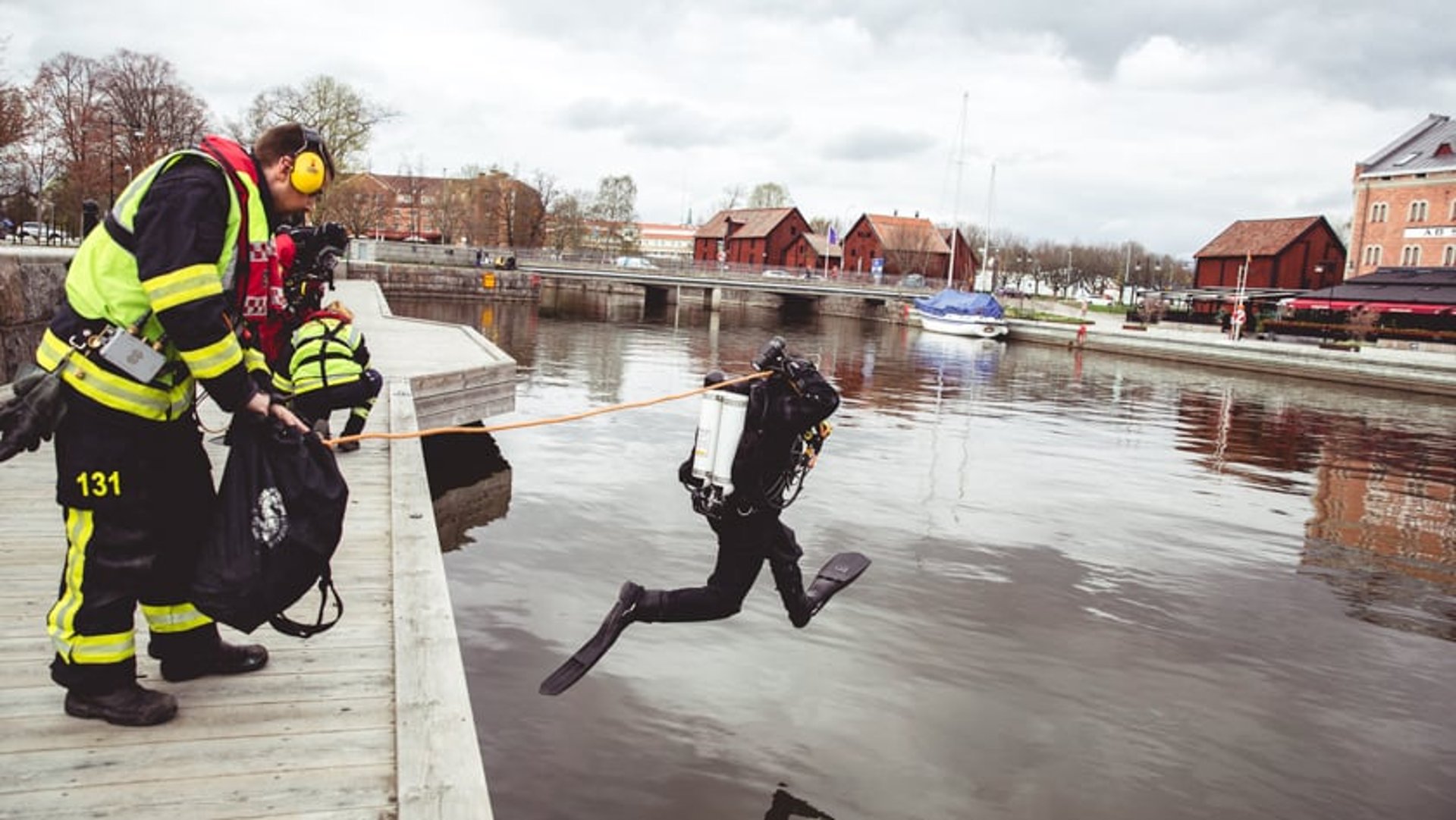 En dykare som hoppar i vattnet från en kaj