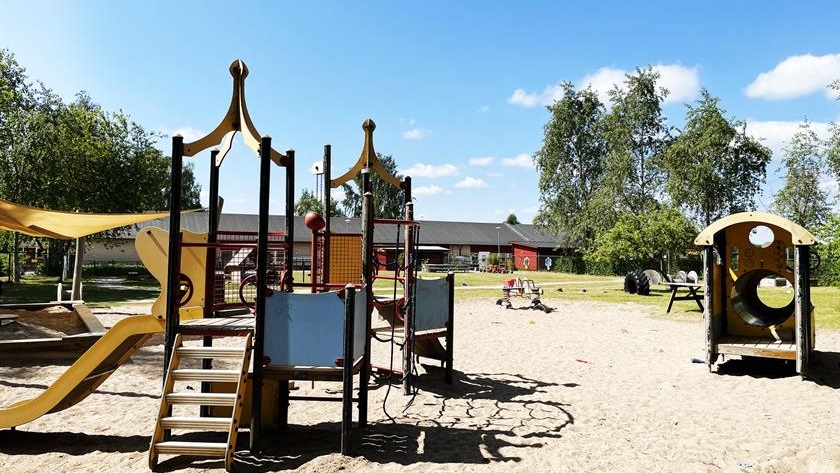 Del av gården med lekställningar och sandlåda.