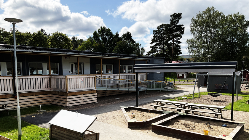 Byggnad och gård med sandlådor, gungor och lekställningar på Stenkulla förskola